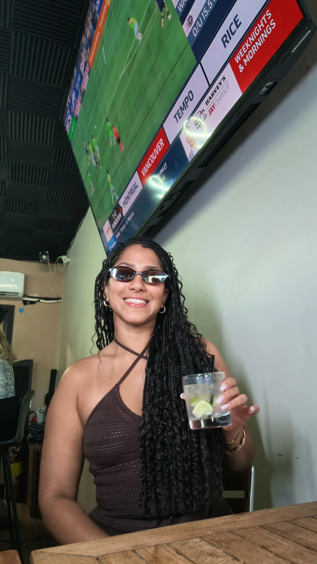 Guest holding a drink under a screen showing a live match