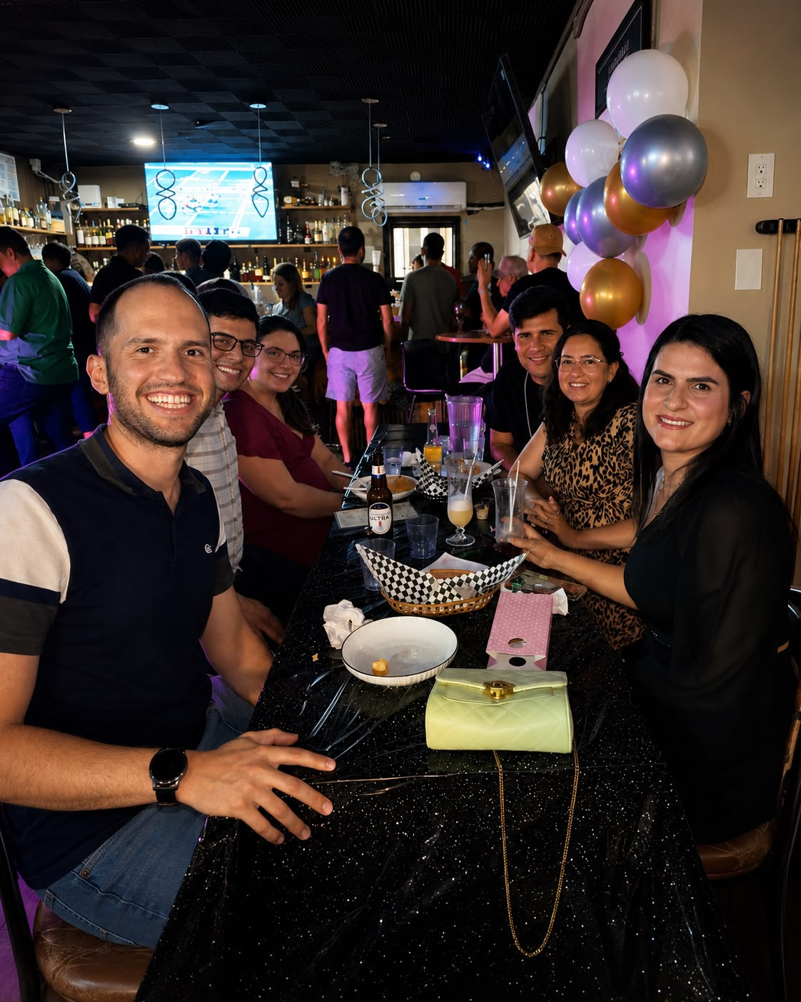 A long table of friends celebrating with balloons at Roots Bar