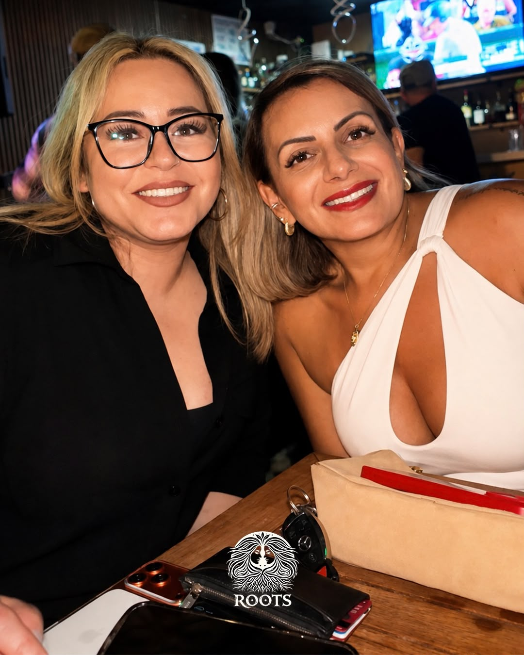Two friends smiling at the bar at Roots Bar